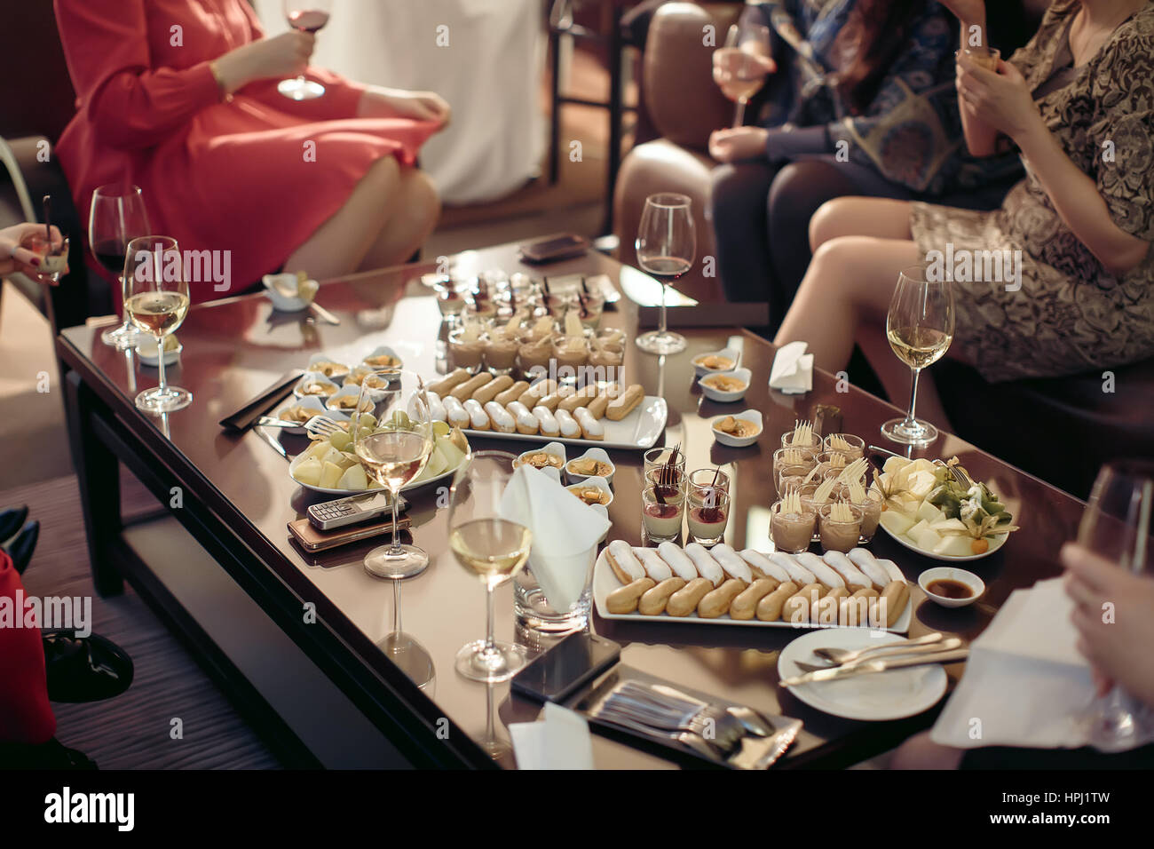 Dessert a buffet con vino circondati gambe femmina Foto Stock