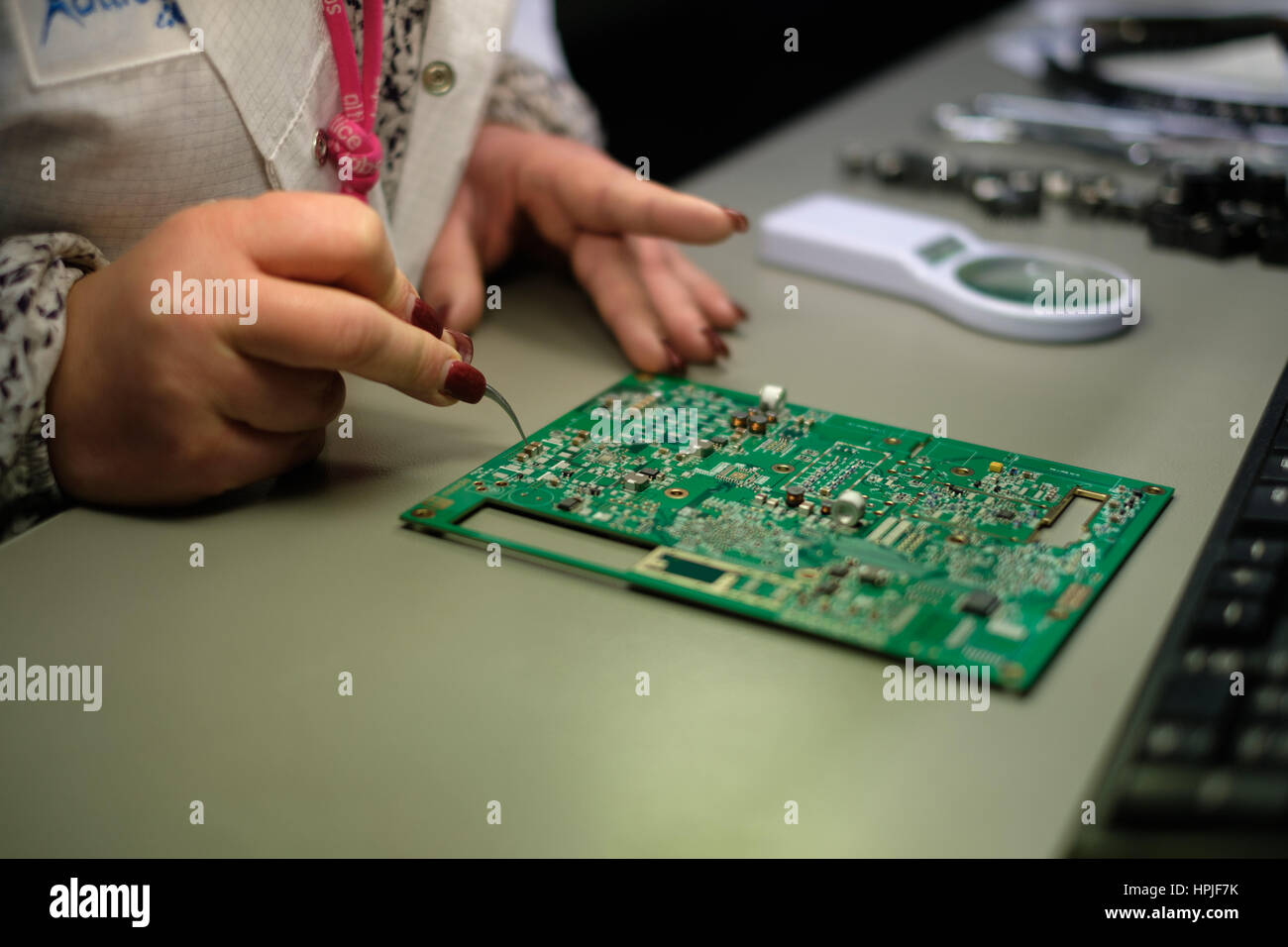 Close up di un lavoratore di sesso femminile che sperimentazione elettronica scheda di circuito Foto Stock
