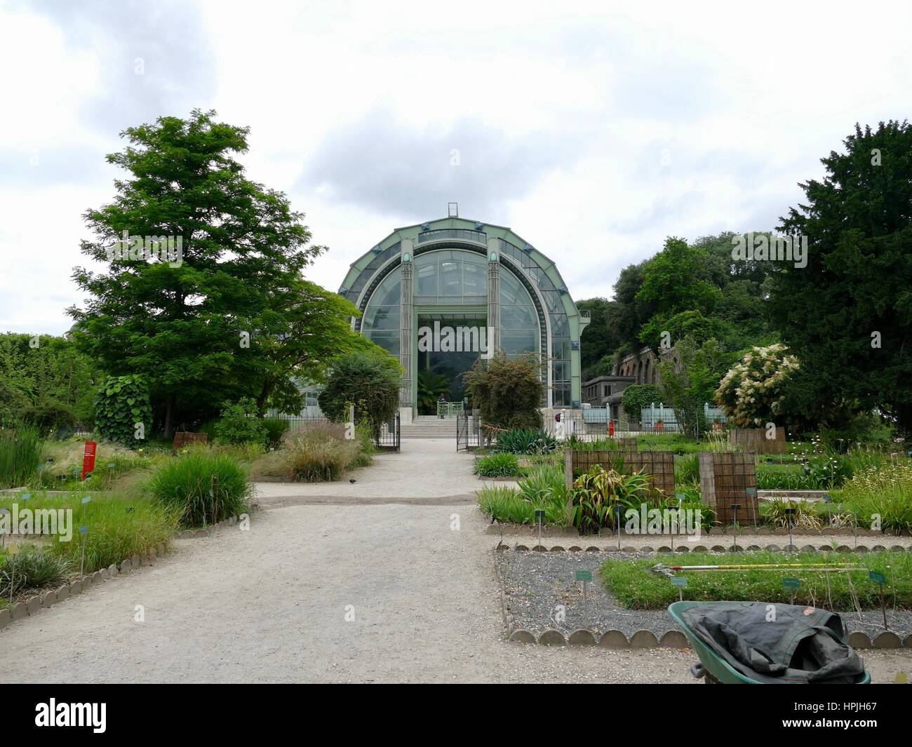 Vista di una grande serra per le piante tropicali in giù un giardino lungo il percorso. Jardin des Plantes, Parigi, Francia. Foto Stock