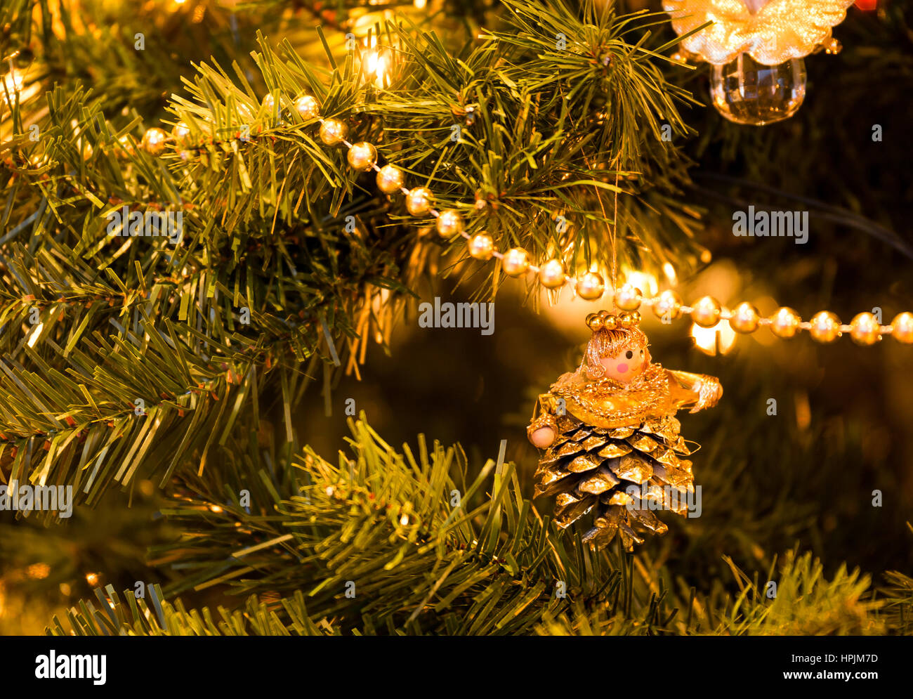 Close up di Angelo decorazione realizzata dal cono di pino su albero di Natale con le luci e la stringa di perle Foto Stock