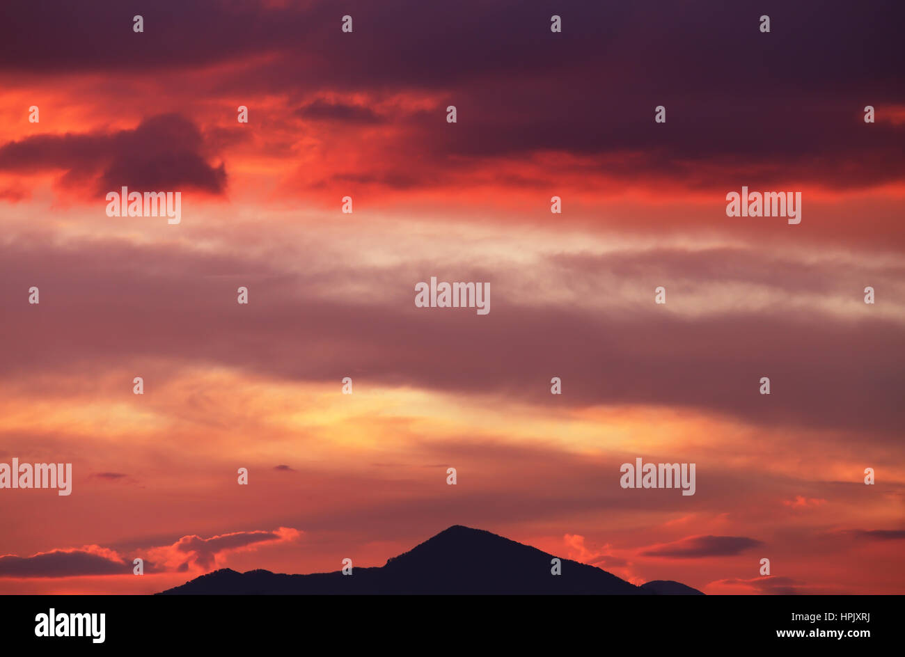 Nuvoloso del cielo della sera in rosso e rosa colori nel picco di montagna Foto Stock
