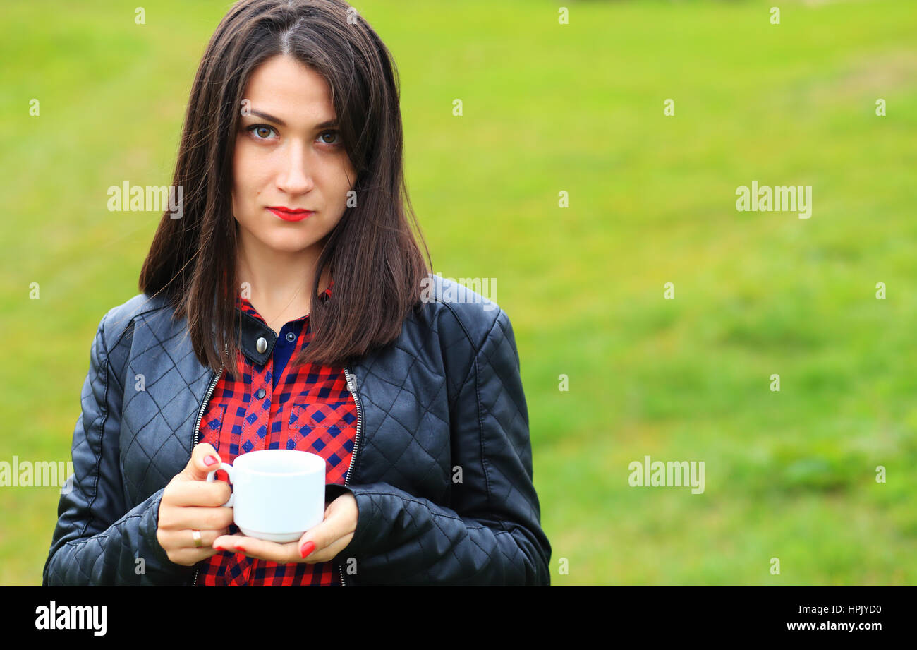 Giovane donna gravi con il bianco tazza di caffè all'aperto Foto Stock