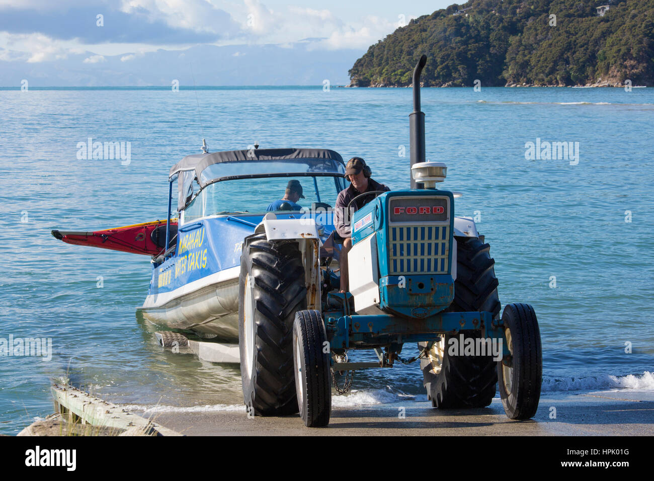 Marahau, Tasmania, Nuova Zelanda. Il traino del trattore tipico Parco Nazionale Abel Tasman acqua taxi, kayak legato alla barca di poppa. Foto Stock
