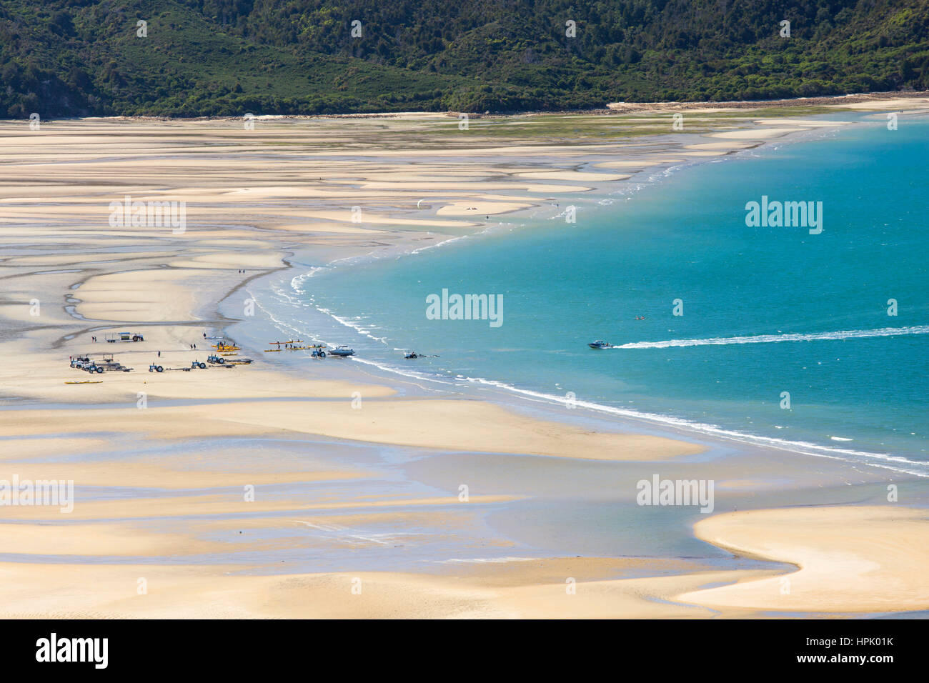 Marahau, Tasmania, Nuova Zelanda. Visualizzare con la bassa marea sulla baia sabbiosa di La costa del Parco Nazionale di Abel Tasman, taxi d'acqua avvicinando alla spiaggia. Foto Stock