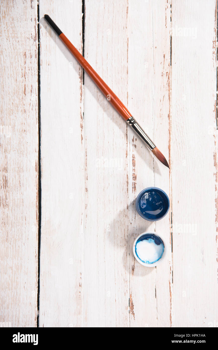 Vista superiore del blu aperto gouache contenitore di vernice e pennello su sfondo di legno Foto Stock