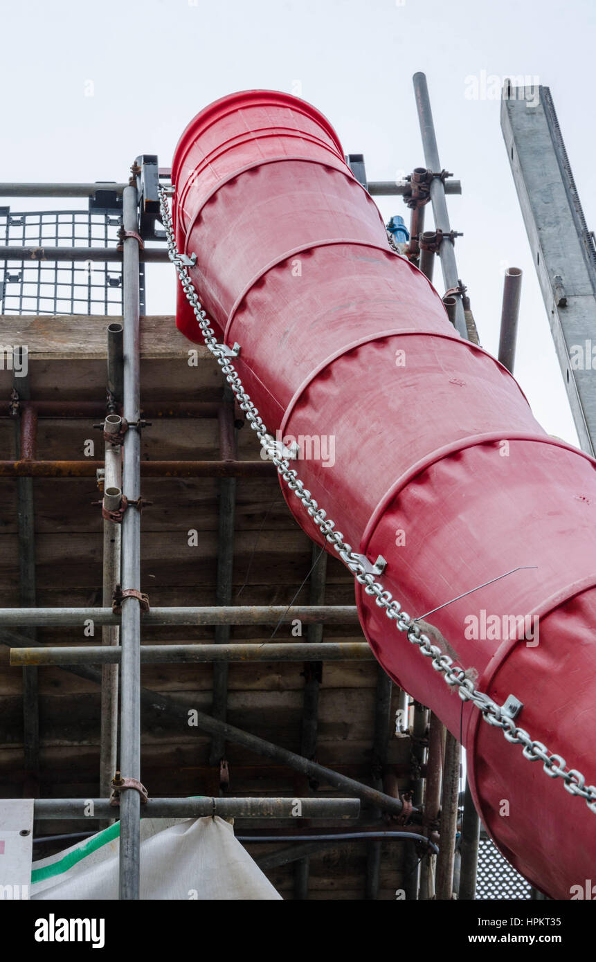 Un spazzatura scivolo consente ai costruttori per eliminare in modo sicuro i rifiuti dalla cima di una torre di ponteggi. Foto Stock