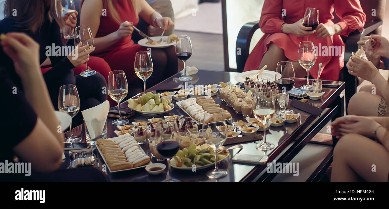 Dessert a buffet con vino circondati gambe femmina Foto Stock