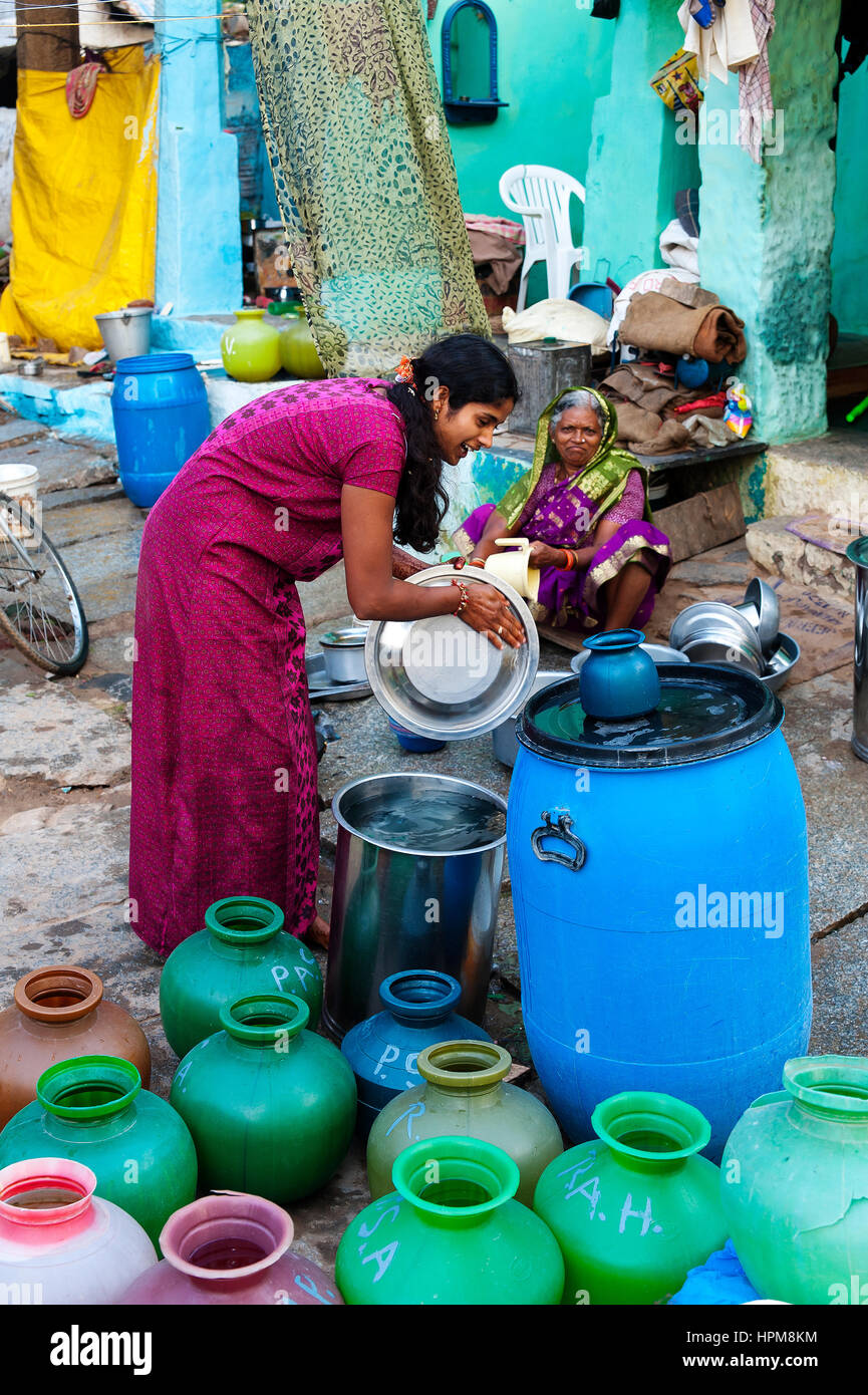 Ragazza indiana il riempimento di contenitori di acqua al Bazaar Street di Hampi, Karnataka, India Foto Stock