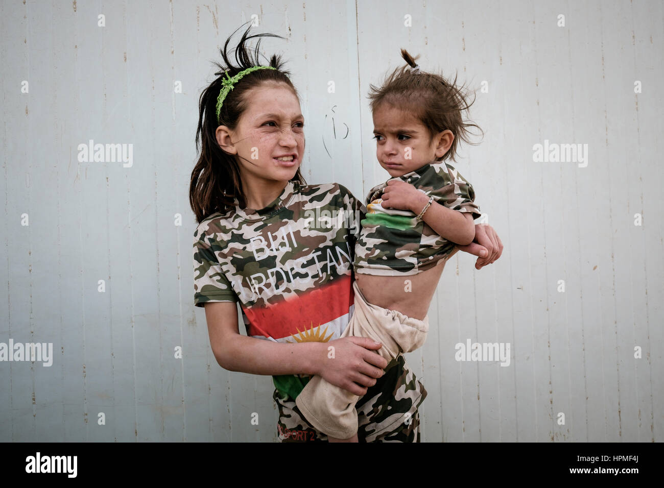 Una giovane ragazza trascinando il suo bambino sorella entrambi indossare magliette con slogan BIJI KURDISTAN (Evviva il Kurdistan) al di fuori di una scuola vicino alla città di sunny, iraq Foto Stock