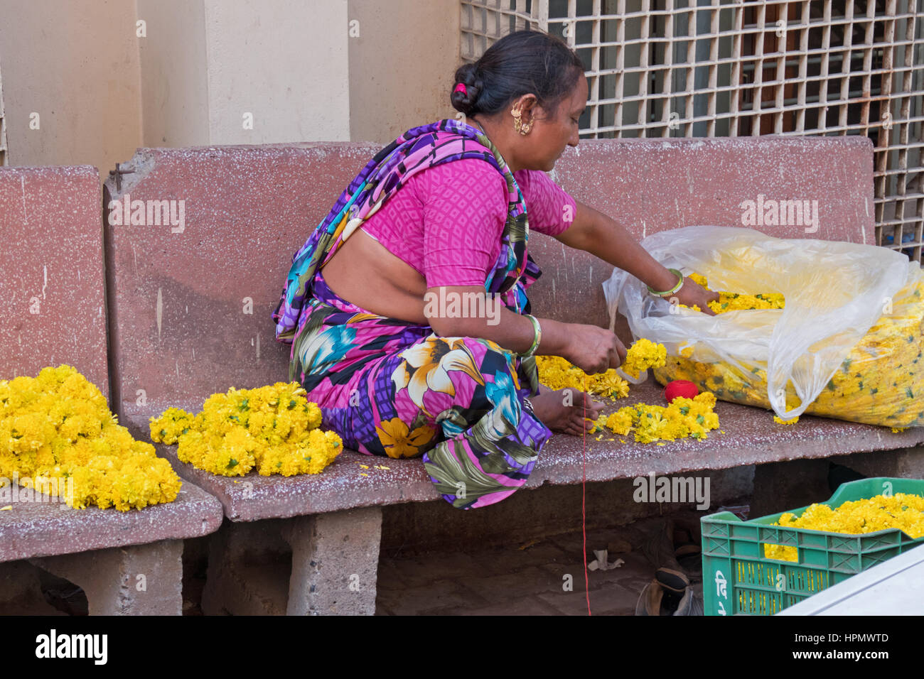 La donna non identificato in un Ahmedabad backstreet fare ghirlande di fiori di tagete per la vendita di adoratori come offerte in un vicino tempio indù Foto Stock
