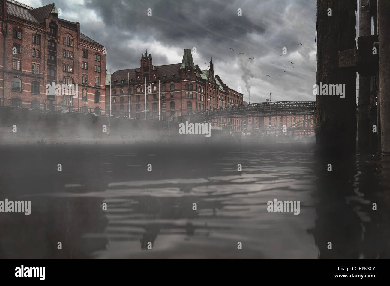 Basso angolo vista sull'acqua del vecchio quartiere di magazzino Speicherstadt di Amburgo, Germania sulla giornata uggiosa Foto Stock