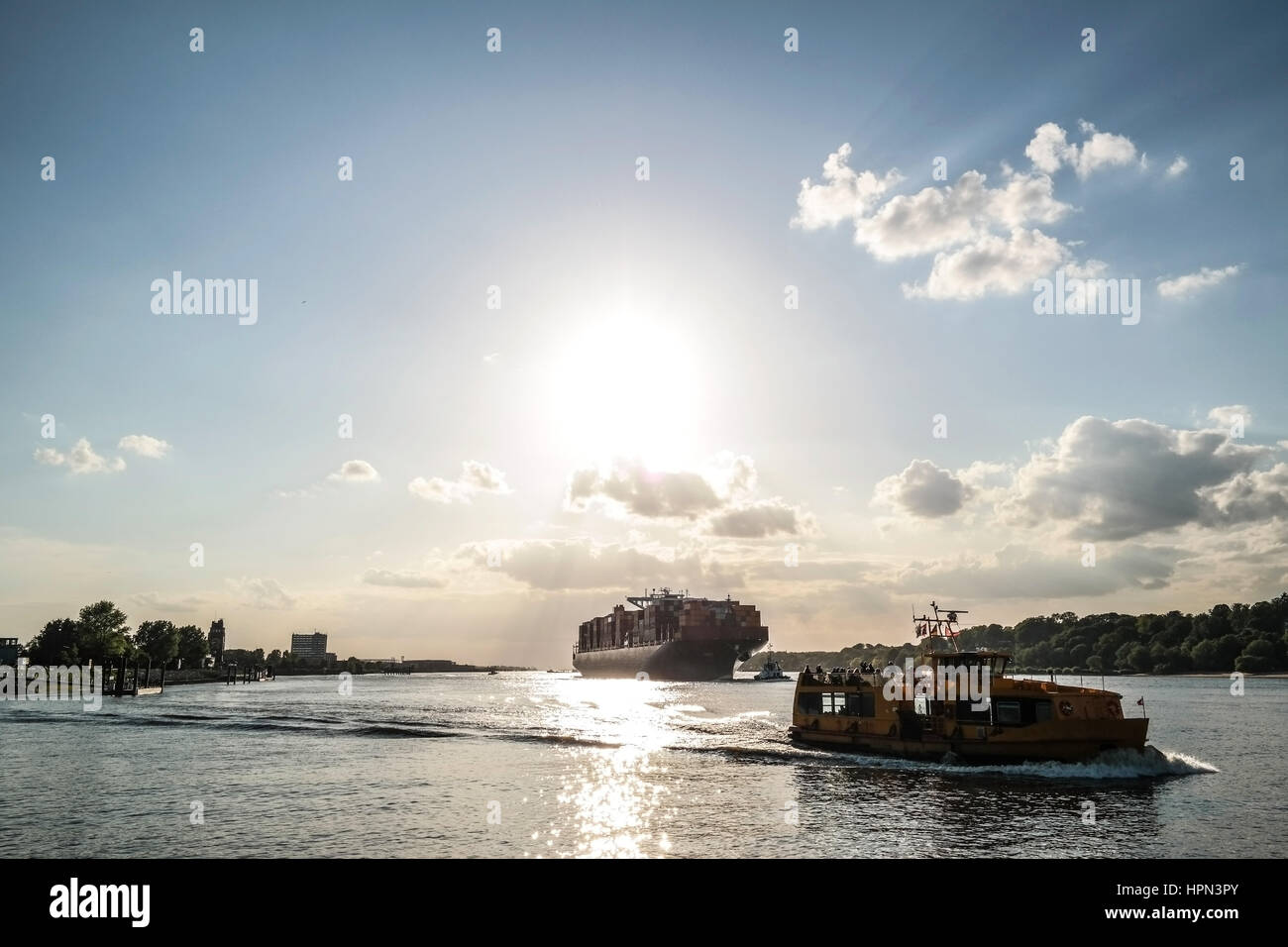 Grande nave portacontainer e navi in acqua sotto il cielo blu con nuvole di luce Foto Stock