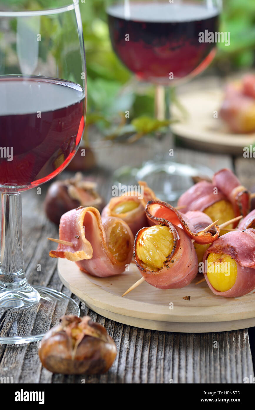 Le caldarroste avvolto in Sud speck tirolese servita su spiedini con vino rosso locale Foto Stock