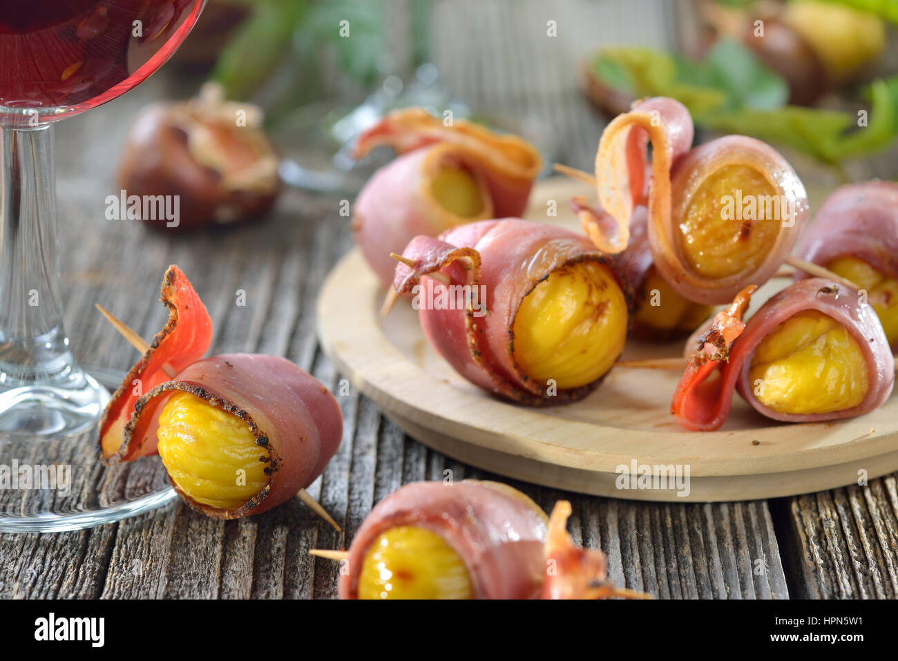 Le caldarroste avvolto in Sud speck tirolese servita su spiedini con vino rosso locale Foto Stock