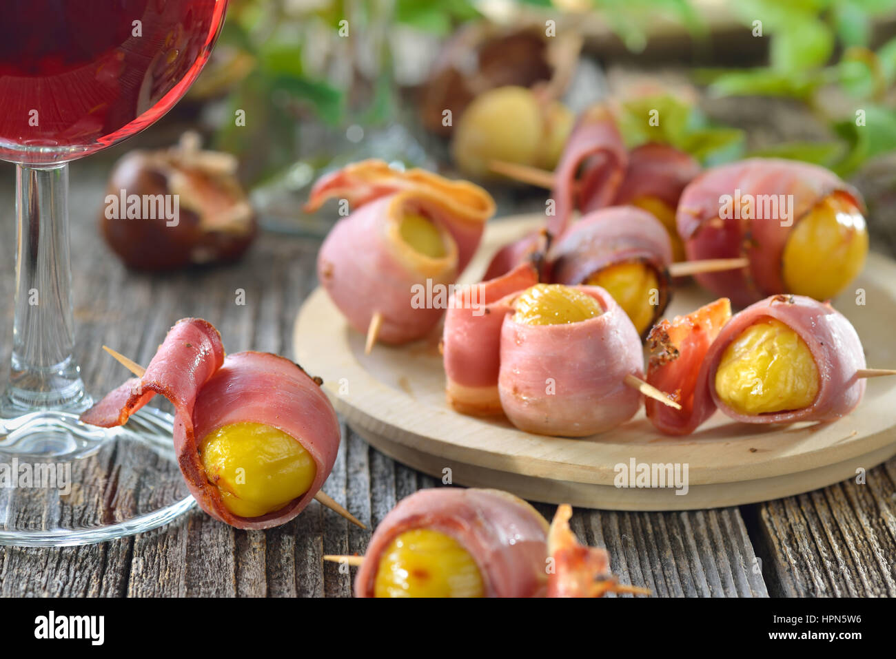 Le caldarroste avvolto in Sud speck tirolese servita su spiedini con vino rosso locale Foto Stock