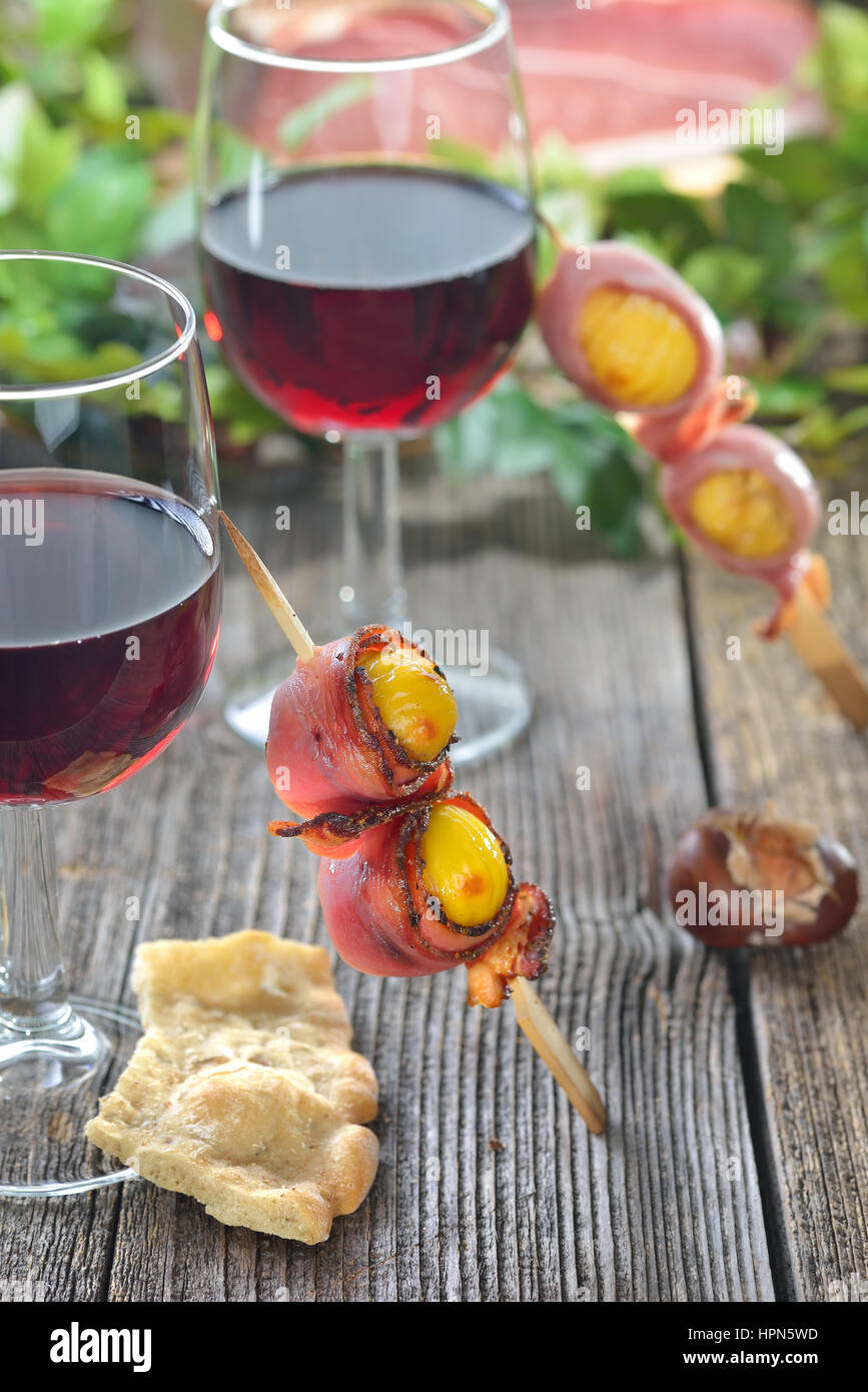Le caldarroste avvolto in Sud speck tirolese servita su spiedini con vino rosso locale Foto Stock
