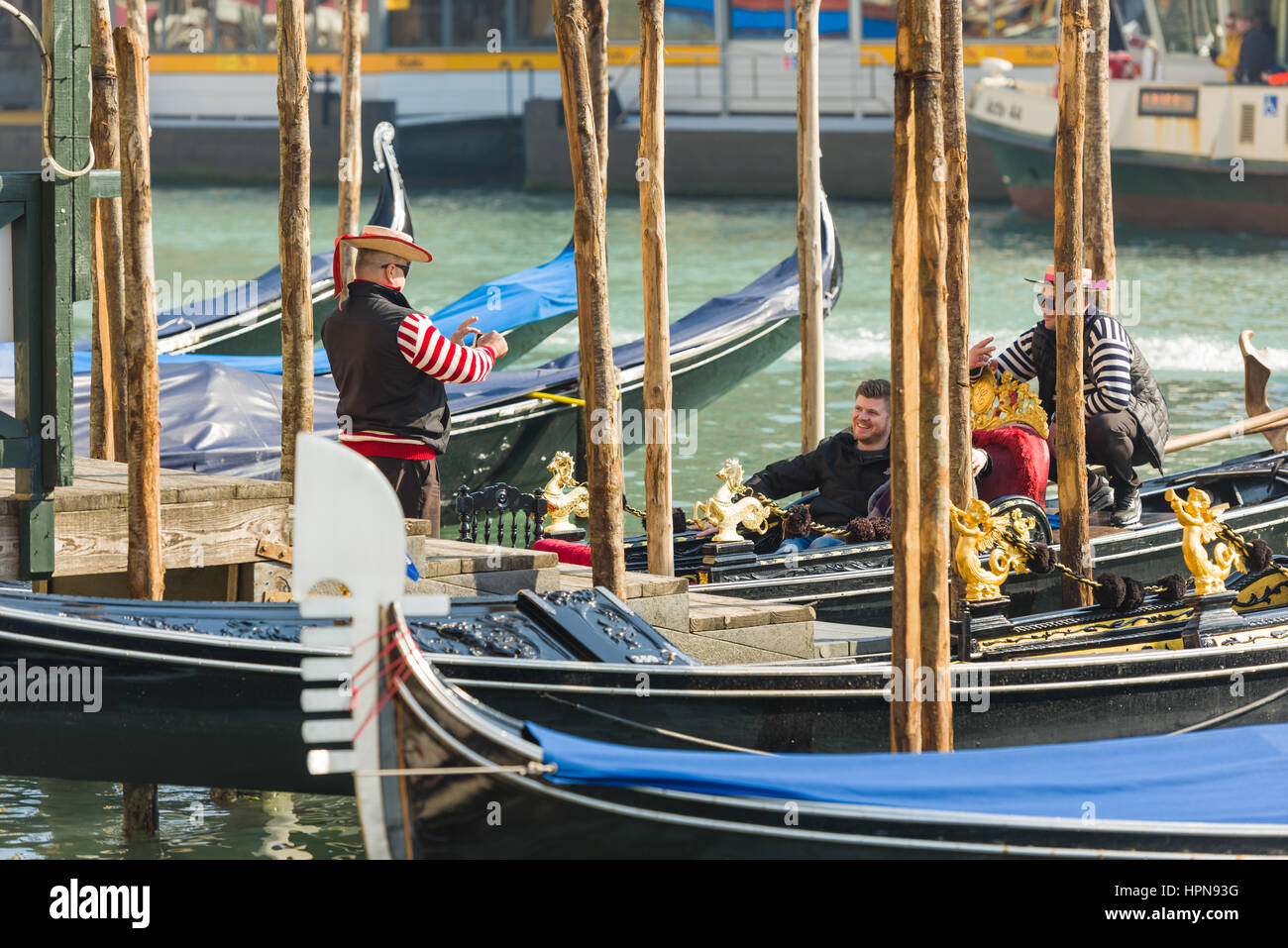 Attenzione PG: gondoliere prende fotografia di turisti a Venezia, Italia. Sullo sfondo un altro gondoliere può essere visto facendo un segno v Foto Stock