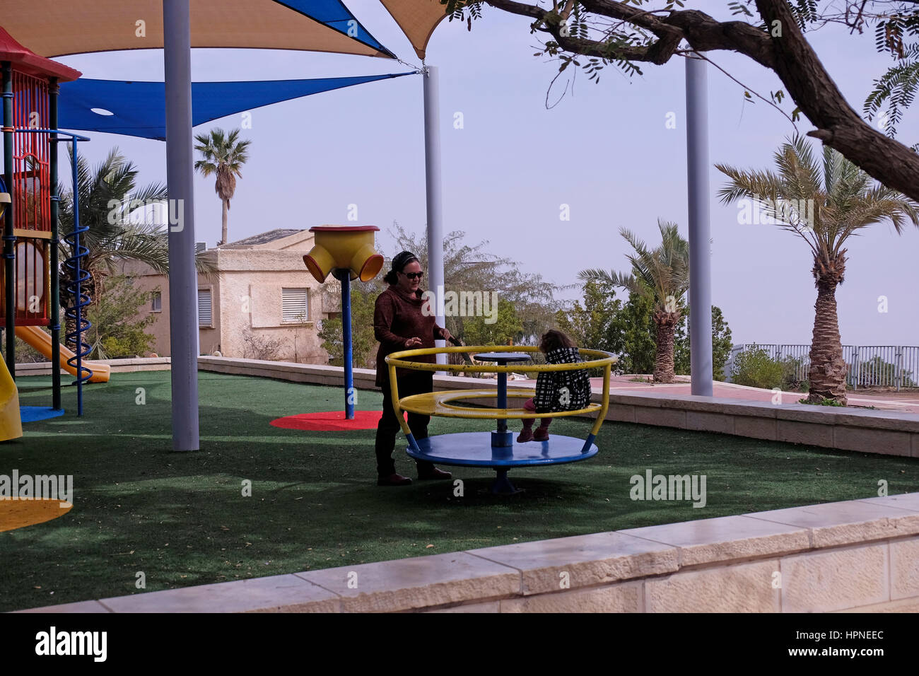 Un colono ebraico giocando con la figlia in un parco giochi all'insediamento ebraico di Mitzpe Yeriho situato a est di Gerusalemme nel deserto della Giudea Cisgiordania Israele Foto Stock