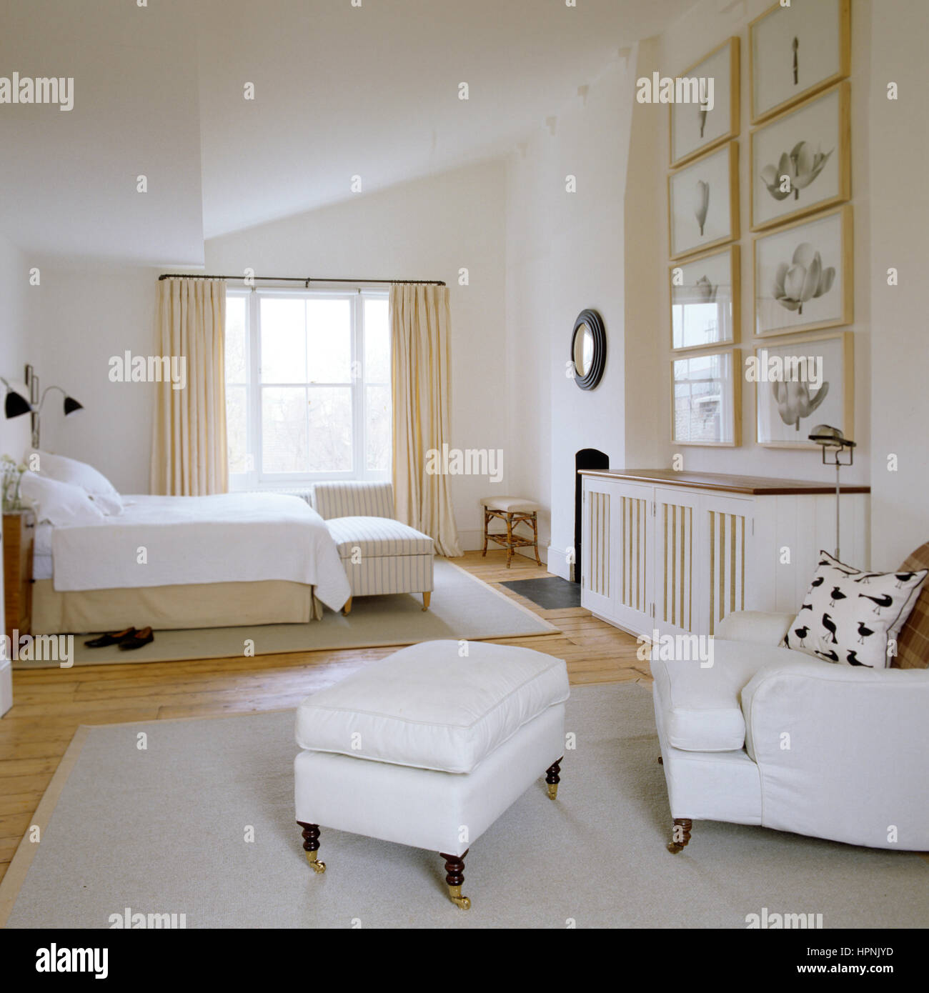 Una camera da letto con una poltrona e ottomana Foto stock - Alamy