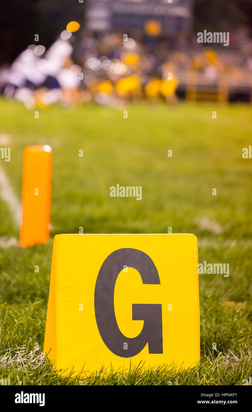 Il giallo il football americano traguardo linea marker al campo scuola con lo studente gli atleti sul campo Foto Stock