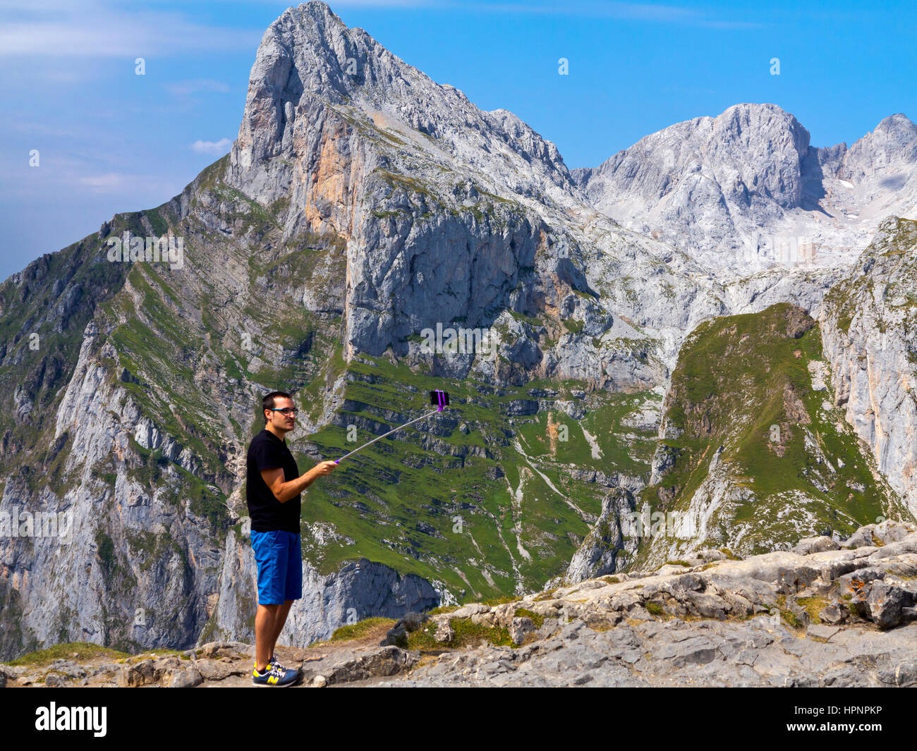 Uomo che utilizza un bastone selfie nel paesaggio di montagna a Fuente De nel Parco Nazionale Picos de Europa Cantabria Spagna settentrionale Foto Stock