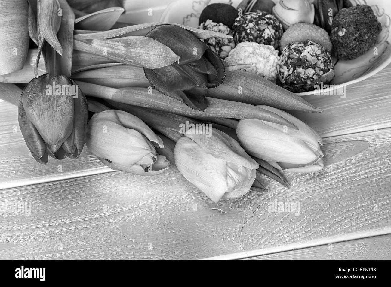 I tulipani bouquet e cioccolato artigianale candys sfondo di legno. In bianco e nero Foto Stock