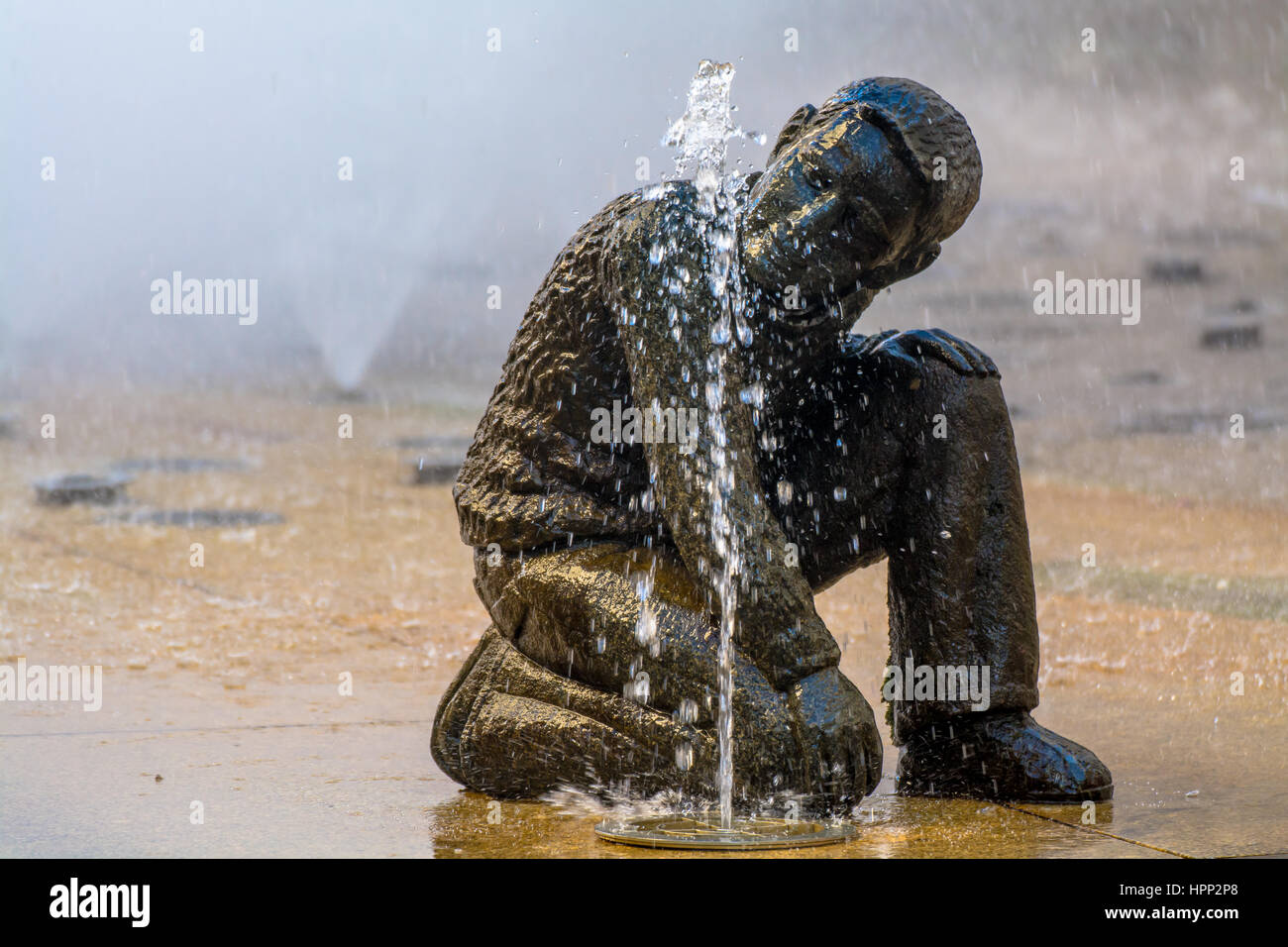 Vista laterale della statua in bronzo di bere il ragazzo Foto Stock