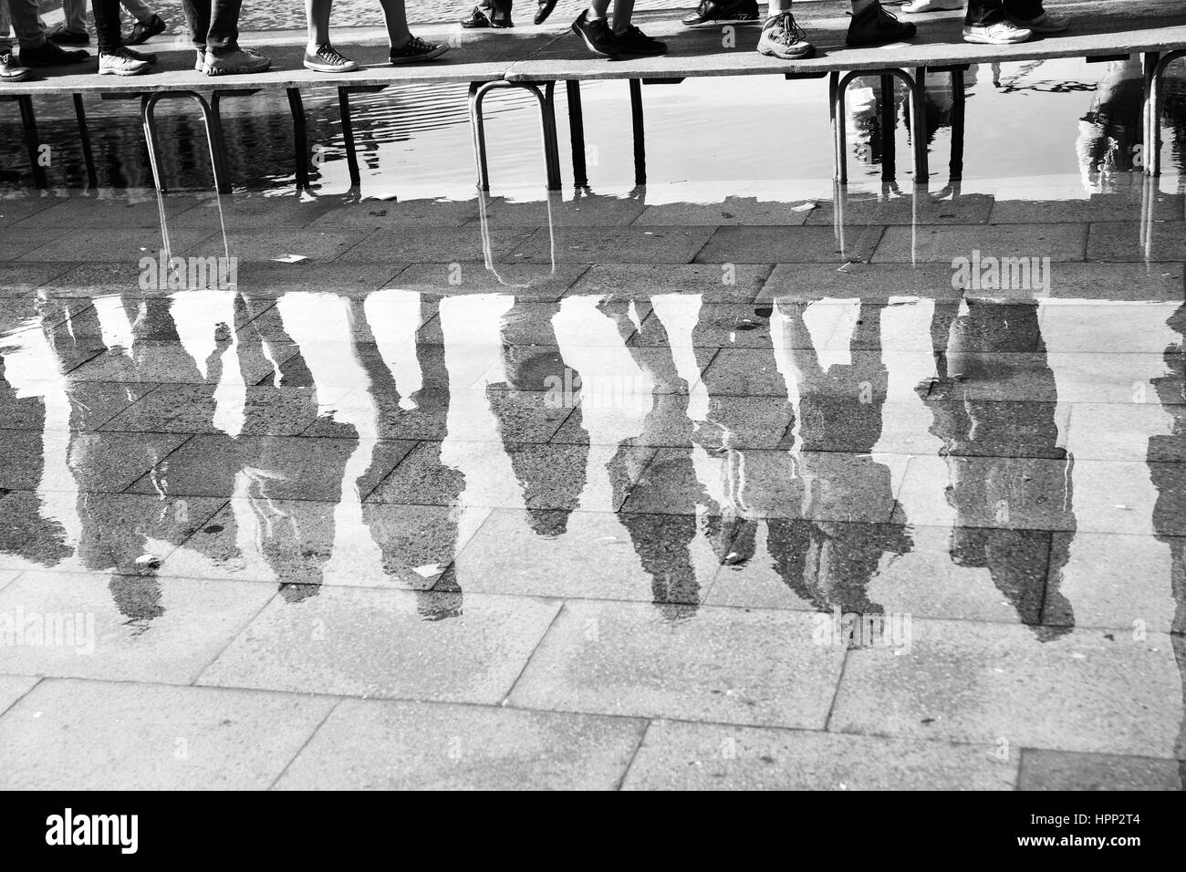 Acqua alta a Venezia - persone a piedi ponte riflettono in una enorme pozzanghera sulla piazza San Marco a Venezia, Italia. Immagine in bianco e nero Foto Stock