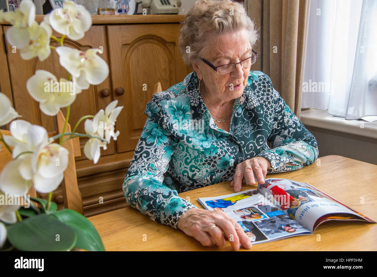 Vecchia donna caucasica la lettura a tavola Foto Stock