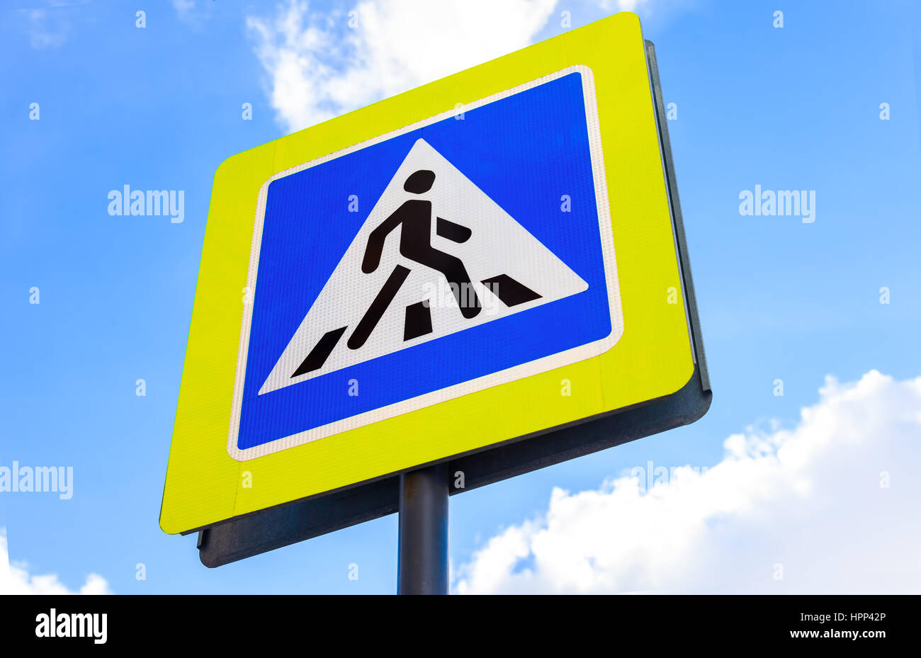 Segno del traffico di attraversamento pedonale contro il cielo blu sullo sfondo Foto Stock