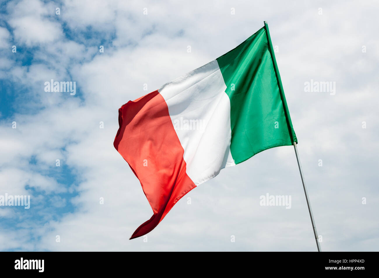 Sventola bandiera italiana contro il cielo nuvoloso Foto Stock