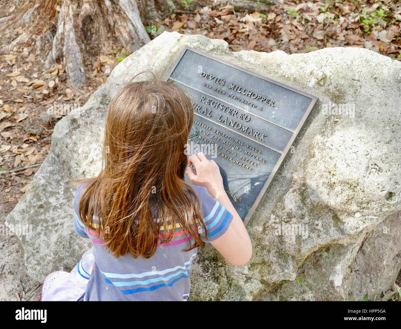 Giovane ragazza di placca di lettura che designa Devil's Millhopper registrati come monumento naturale. Stato geologico Park. Gainesville, Florida, Stati Uniti d'America Foto Stock