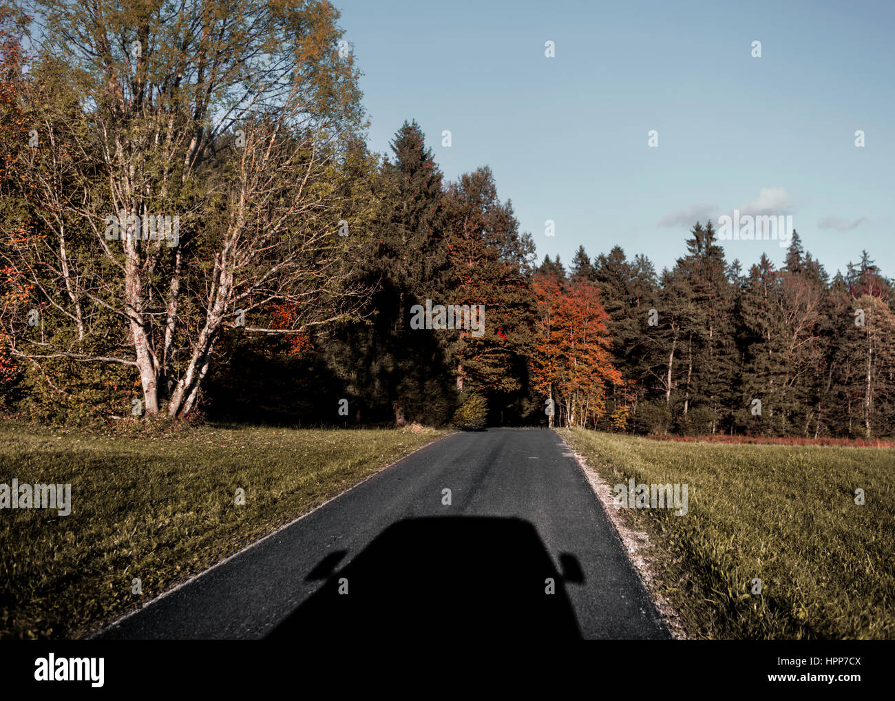 Ombra del veicolo per il trasporto di persone su strada di campagna in autunno Foto Stock