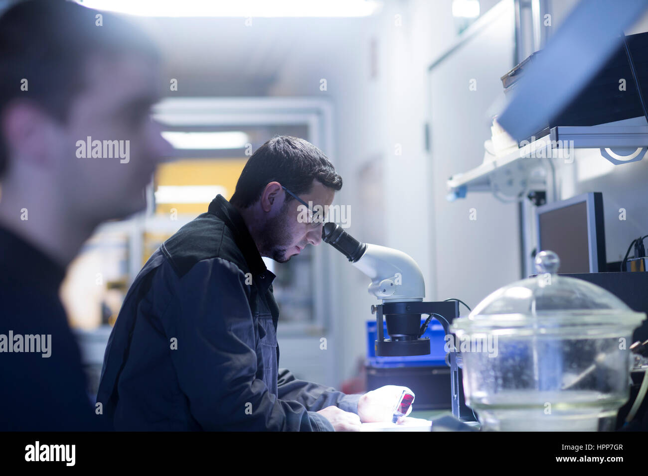 Uomo che utilizza un microscopio in una tecnologia di sensore impianto Foto Stock