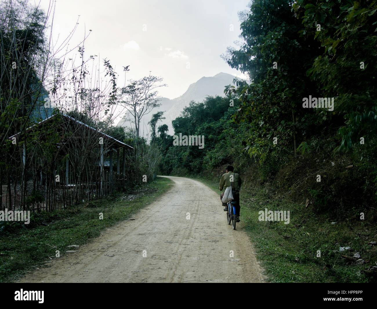Asian ciclista su strada sterrata in naturale ambiente rurale Foto Stock