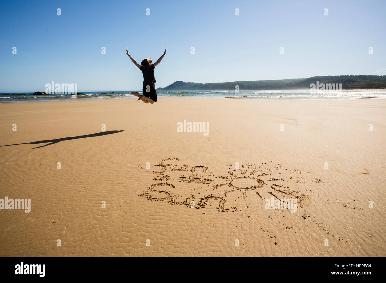 Donna che si tuffa per il divertimento sulla spiaggia sabbiosa, divertimento al sole scritto in sabbia, Croajingolong, Victoria, Australia Foto Stock