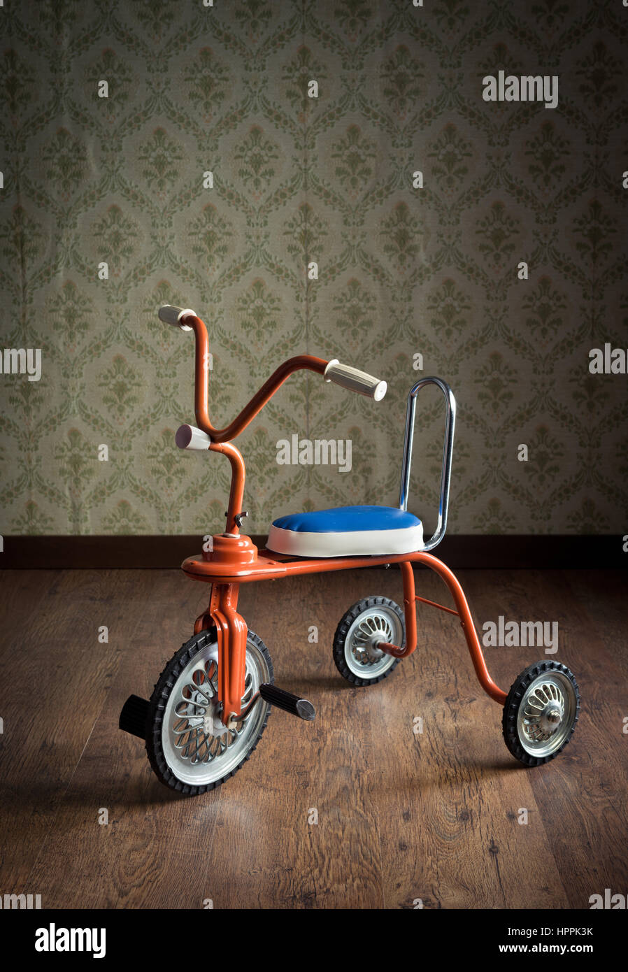 Vintage triciclo arancione sul pavimento di legno e carta da parati vintage  sullo sfondo Foto stock - Alamy