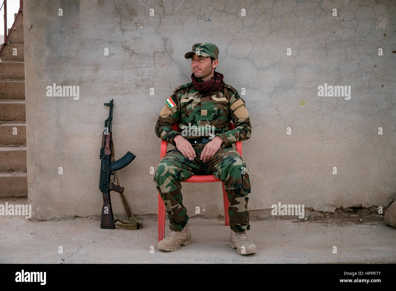 Yazidi Peshmerga Fighter si siede di protezione a un cui bace sulla linea del fronte con stato islamico al piede della montagna di Sinjar Foto Stock