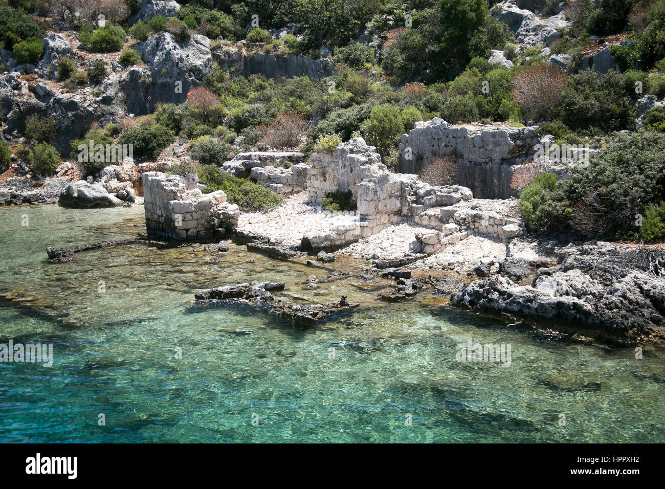 Città Sommersa di Kekova nella baia di Uchagiz vista dal mare in provincia di Antalya in Turchia con turqouise rocce del mare e il verde delle boccole con resti di antichi Foto Stock