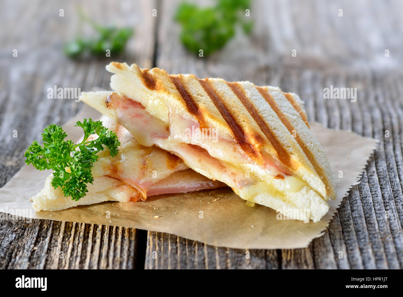 Premuto e tostare panini doppia con prosciutto e formaggio servita su carta a sandwich su un tavolo di legno Foto Stock