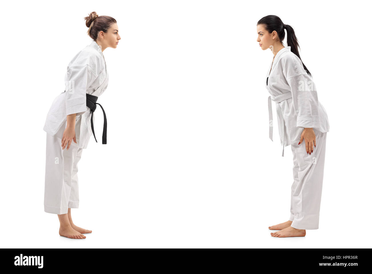 A piena lunghezza profilo colpo di due giovani donne vestite in kimono si inchinano a ogni altro isolato su sfondo bianco Foto Stock