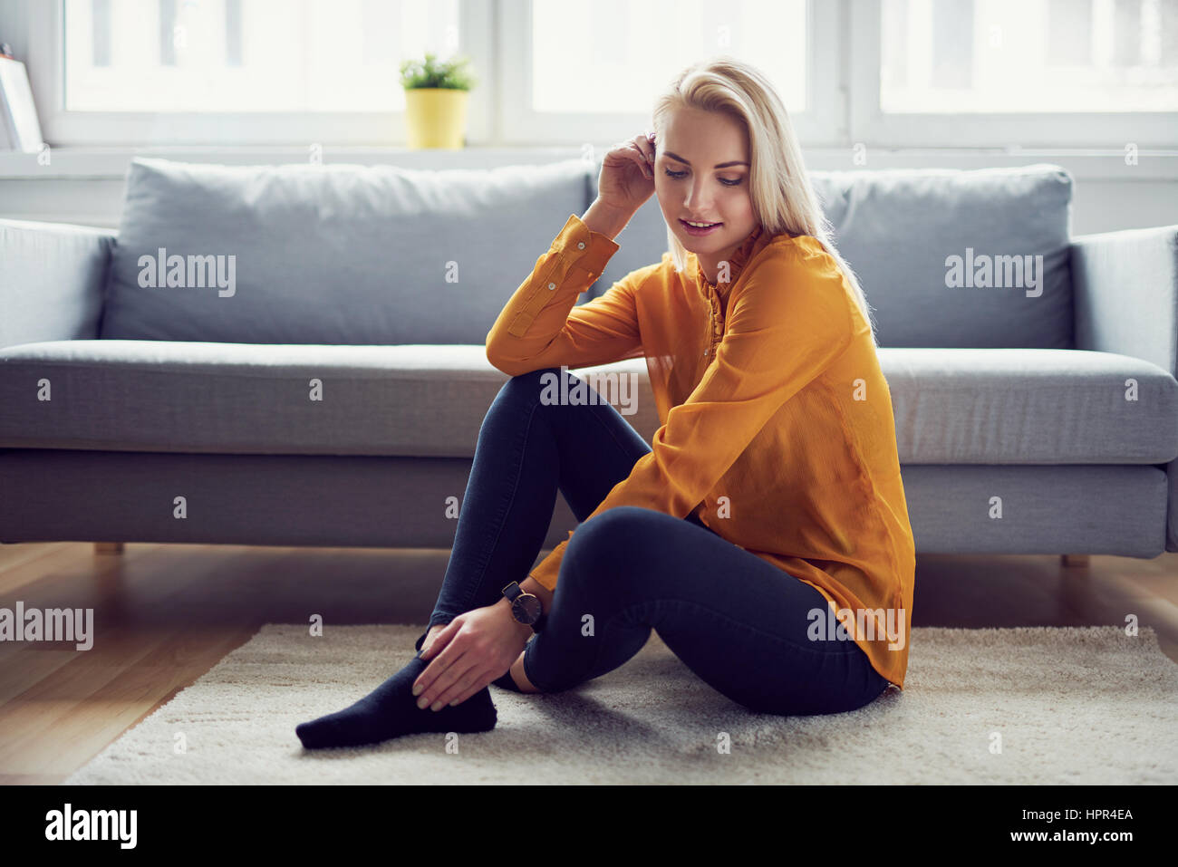 Ritratto di donna attraente seduto sul tappeto in salotto Foto Stock