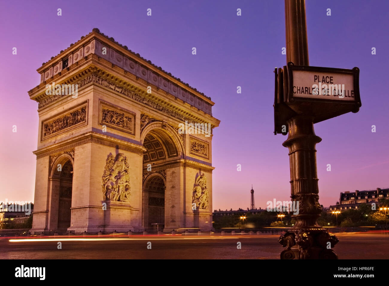 Alba all'Arc de Triomphe in Paris, Francia. Un segno su un lampione legge Place Charles de Gaulle e la Torre Eiffel è visibile in lontananza. Foto Stock