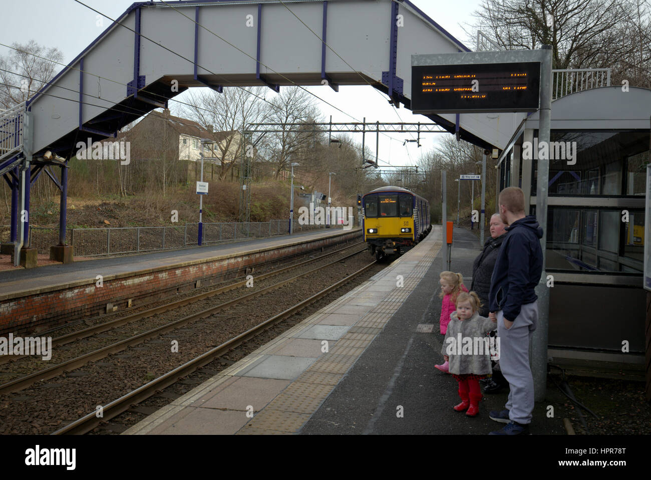 Famiglia di passeggeri in attesa di arrivare con il treno alla stazione di Drumchapel Glasgow Foto Stock