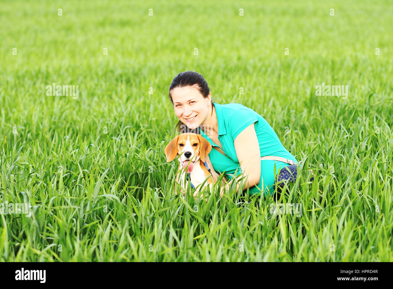 Giovane donna felice con cane beagle in erba verde Foto Stock