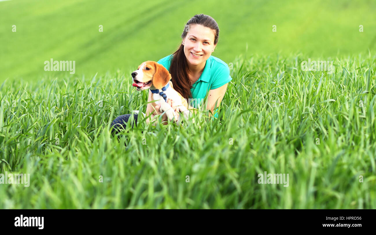 Felice ragazza con cane beagle in erba verde Foto Stock