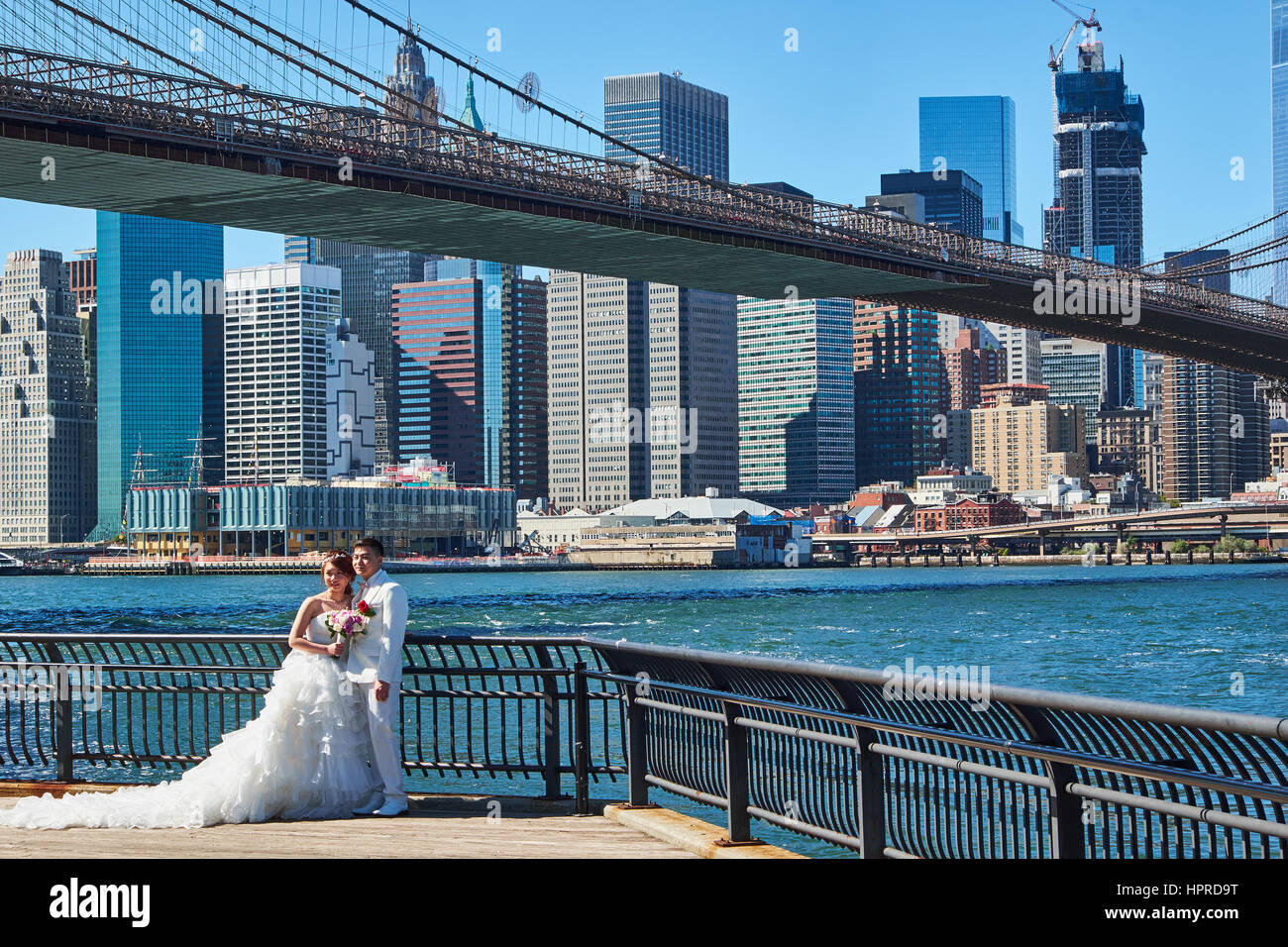 DUMBO, NEW YORK - 25 settembre 2016: coppie in viaggio di nozze in piedi su un molo a Dumbo di Brooklyn con ponte di Brooklyn in background Foto Stock