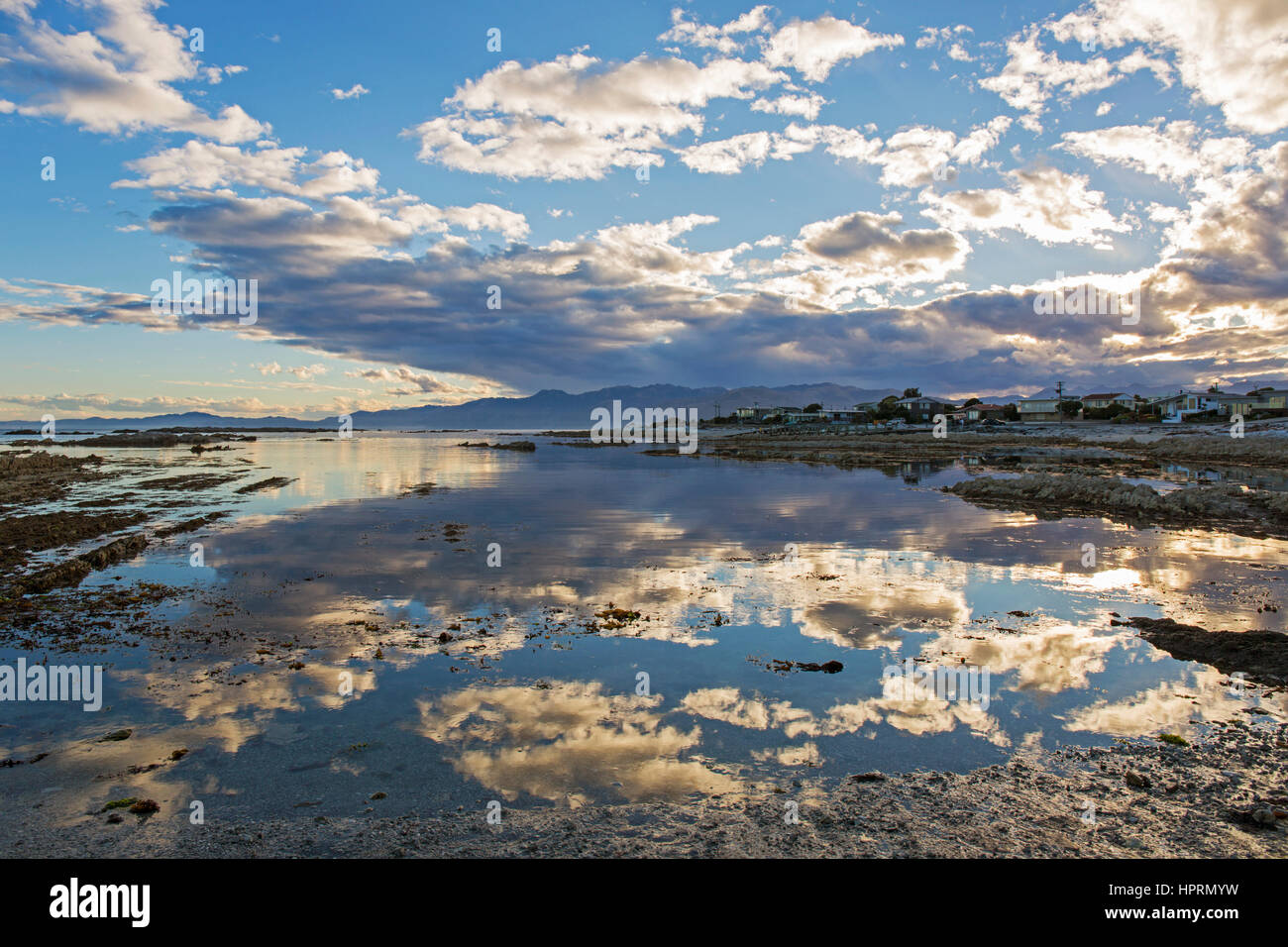 Kaikoura, Canterbury, Nuova Zelanda. Vista su tutta la baia del Sud a sera, cloud-riempito il cielo si riflette ancora in acqua. Foto Stock