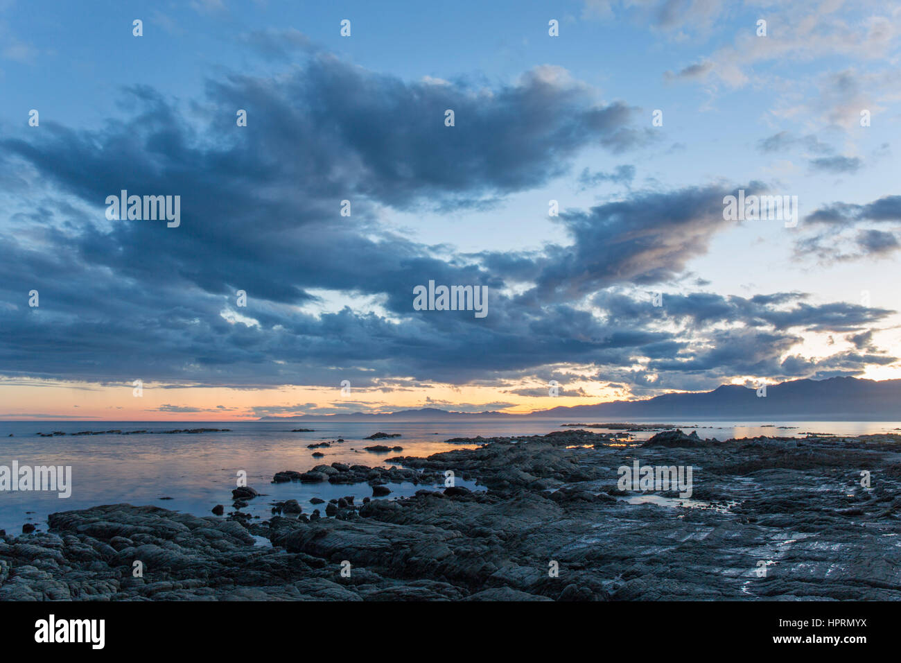 Kaikoura, Canterbury, Nuova Zelanda. Vista su tutta la baia a sud dalla spiaggia rocciosa al crepuscolo. Foto Stock