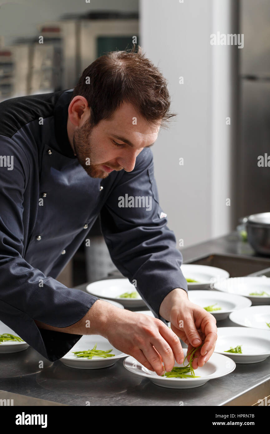 Il giovane chef in hotel o al ristorante cucina cucina per il pranzo Foto Stock